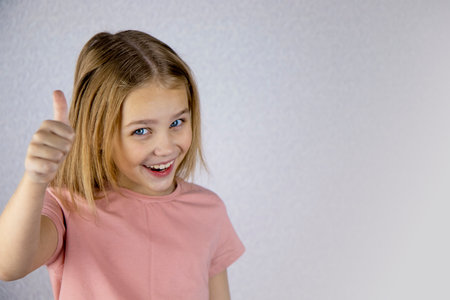 Laughing girl with daisy in her hair, showing thumbs up.の写真素材
