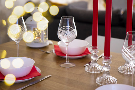Side view of the Christmas setting of the festive table. Beautiful white kitchen appliances on the background of specks of a garland of bokeh. The concept of holidays with the familyの写真素材
