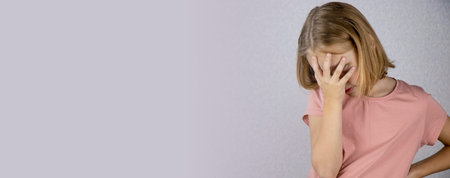 The little girl keeps her hands on her forehead. She is upset or depressed. expression of emotions