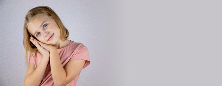 Portrait of a cute girl on a light background, a little blonde looks at the camera and smiles. The concept of joy, happiness and good mood. copyspace.の写真素材