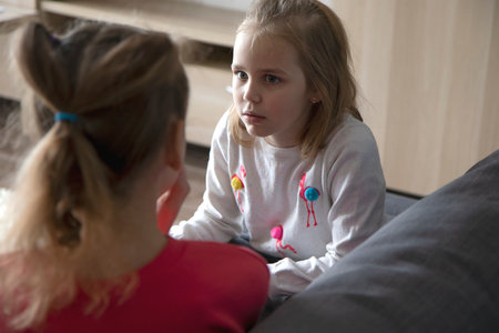 A teenage girl and her sister look at each other and talk about important things while sitting at home. The concept of trusting relationships and help in solving the problem.の写真素材