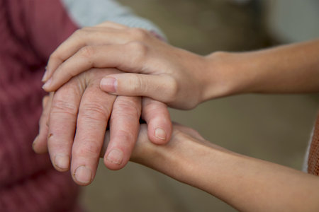 The hands of a young girl hold the bitches of her elderly grandmother. The concept of love and care for the elderly, respect within the family and acceptance of old age.の写真素材