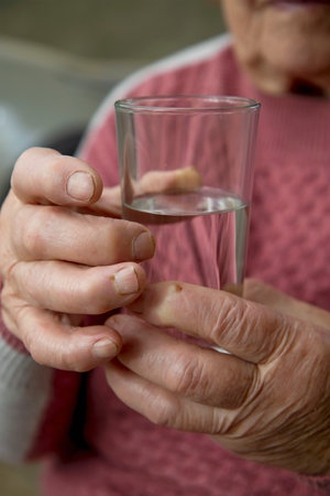 the hands of an elderly woman hold a glass of clean water. The concept of health and proper lifestyle in old and old age.の写真素材