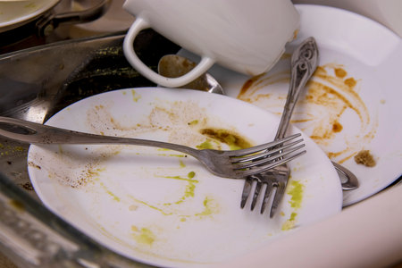 A pile of unwashed dishes in the sink. Mess and dirt in the kitchen. Dirty plates, mugs and cutlery. Putting the house in order, big cleaning, cluttered houseの写真素材