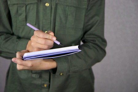 Close-up of a teenage girl making zebras and writing by hand with a pencil in a notebookの写真素材
