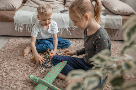 The younger brother and sister are playing with plastic animals and a toy airplane. Development of communication through childrens games. Friendship and cheerful mood.の写真素材