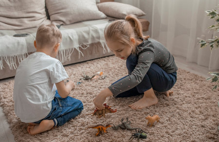 The younger brother and sister play with plastic animals sitting on the floor.Love and friendship within the family, joint leisure.Development of communication skills through the gameの写真素材