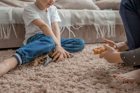 The younger brother and sister are playing with plastic animals, sitting on the floor in the living room.Love and friendship within the family.Development of communication through childrens games.の写真素材