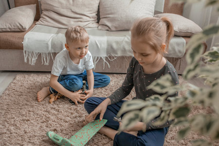 The younger brother and sister are playing with plastic animals and a toy airplane. Development of communication through childrens games. Friendship and cheerful mood.の写真素材