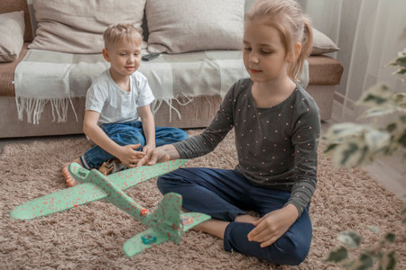 The younger brother and sister are playing with plastic animals and a toy airplane. Development of communication through childrens games. Friendship and cheerful mood.の写真素材