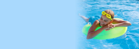 Smiling cute teenage girl wearing swimming glasses and a large swimming circle in the pool on a sunny summer day. Banner.の写真素材