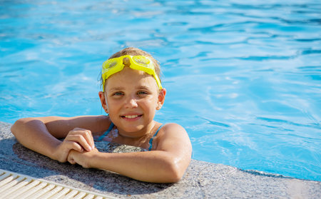 Smiling cute little girl wearing swimming glasses in the pool on a sunny summer day.の写真素材