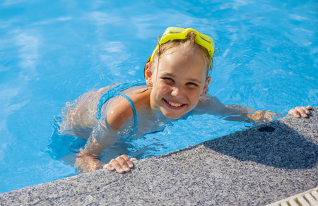 Smiling cute little girl wearing swimming glasses in the pool on a sunny summer day.の写真素材