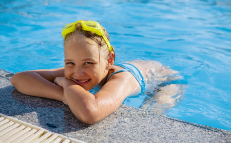 Smiling cute little girl wearing swimming glasses in the pool on a sunny summer day.の写真素材