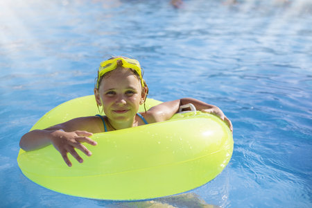 Smiling cute little girl wearing swimming glasses in the pool on a sunny summer day.の写真素材
