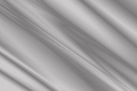 Soft gray fabric cascades gently, showcasing its rich texture and subtle sheen under warm light. The folds create an inviting and calm aesthetic, ideal for cozy settings.の写真素材