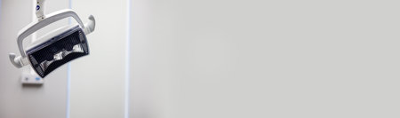 A dental chair apparatus hangs overhead in a well-lit clinic, poised for an upcoming patient examination. The clean, minimalistic design reflects a contemporary healthcare environment.の写真素材