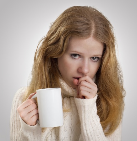 girl sick with the flu coughs, a mug of teaの写真素材