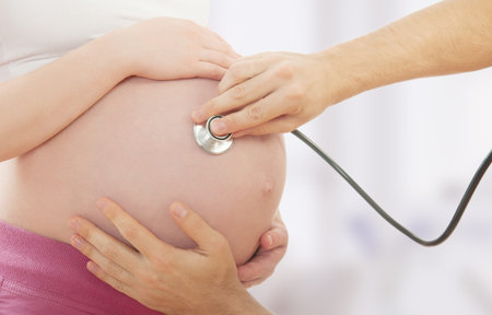 belly of pregnant woman, hand of doctor, stethoscope