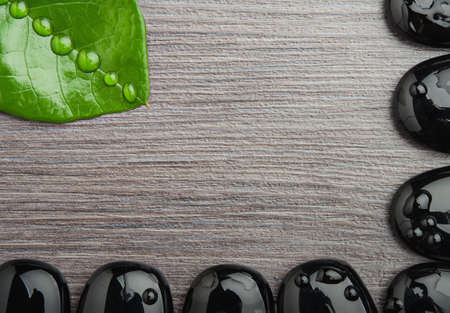 Eco spa background wooden with frame of stones and leaf with water droplets, space for your textの写真素材