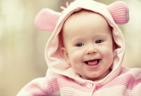 happy smiling cheerful baby girl in pink hood with earsの写真素材