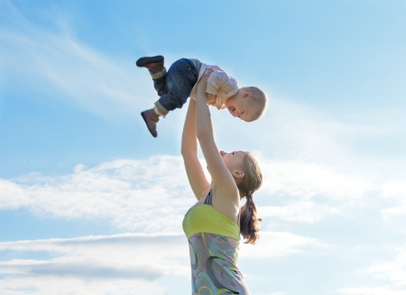 Mother throws up  baby in the sky in nature