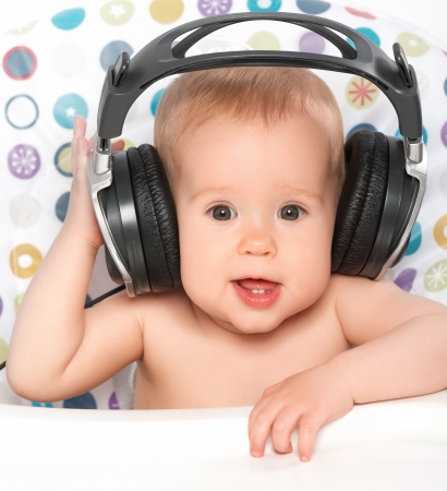 beautiful happy baby with headphones listening to musicの写真素材