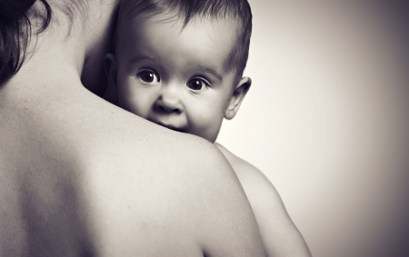cute baby looking at hands of the mother in an embrace, monochromeの写真素材