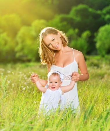 happy family on nature outdoors mother and baby daughter on the green meadow in a white dressの写真素材
