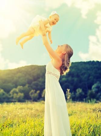 happy family on nature outdoors mother and baby daughter on the green meadow in a white dressの写真素材