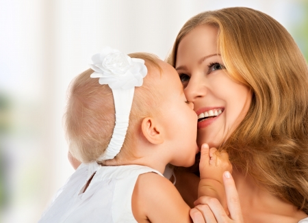 Happy cheerful family. Mother and baby kissing, laughing and huggingの写真素材