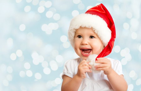 Beautiful funny baby in a Christmas hat  on blue backgroundの写真素材