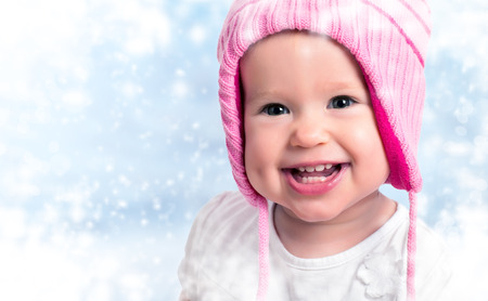 happy baby girl in winter pink hat smiling on outdoorsの写真素材