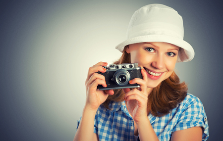 happy young female photographer with retro camera in a hatの写真素材