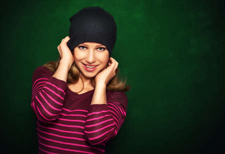 Young beautiful happy girl cheeky teenager in a black hat and a pink dress on a green backgroundの写真素材