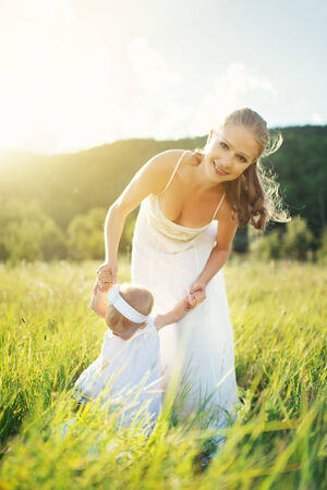 happy family on nature outdoors mother and baby daughter on the green meadow in a white dressの写真素材