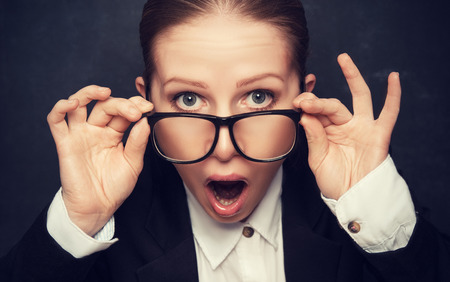 Surprised funny teacher in glasses shouts at the school boardの写真素材