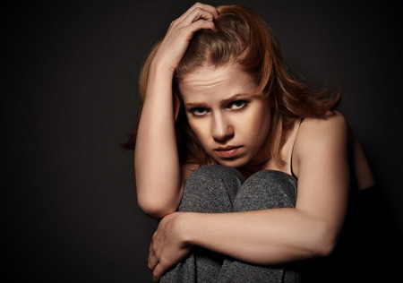 sad woman in depression and despair crying on black dark backgroundの写真素材