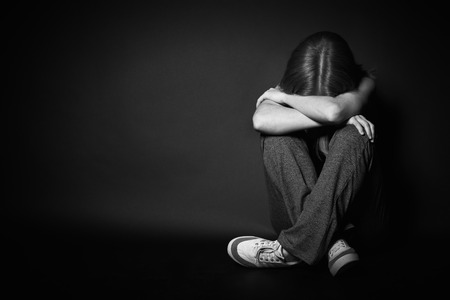 sad woman in depression and despair crying on black dark backgroundの写真素材