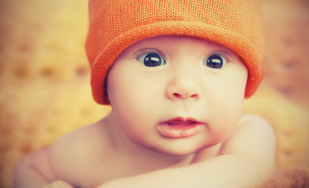 cute happy newborn baby in knitted orange hat capの写真素材