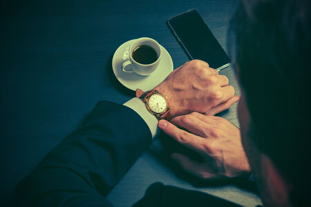 phone and a cup of coffee in the hands of a businessman. stylish business still life in dark colorsの写真素材