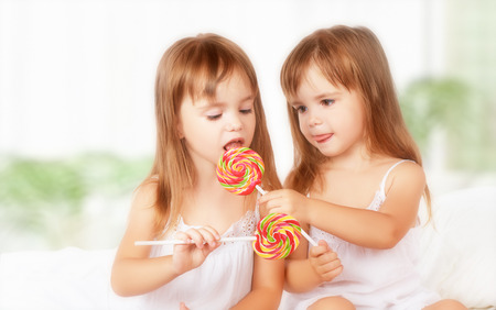 happy girl children twin sisters with lollipops candyの写真素材