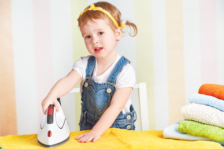 cute little baby girl housewife iron clothes iron, is engaged in domestic workの写真素材