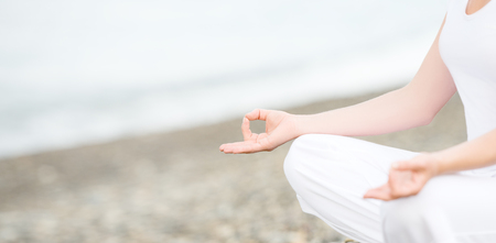 hand of a woman meditating in a yoga pose on the beachの写真素材