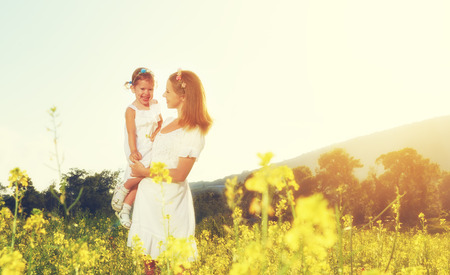 happy family, mother and little daughter girl child in the summer meadow with yellow flowersの写真素材