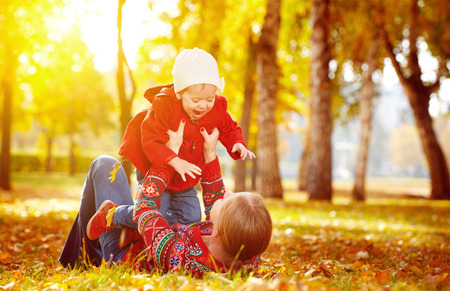 happy family: mother and child little daughter play cuddling on autumn walk in nature outdoorsの写真素材