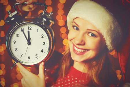 Merry Christmas! Cheerful woman in a Christmas hat with alarm clockの写真素材