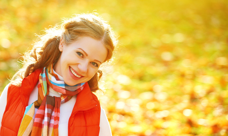 face of a happy girl with autumn leaves on a walkの写真素材