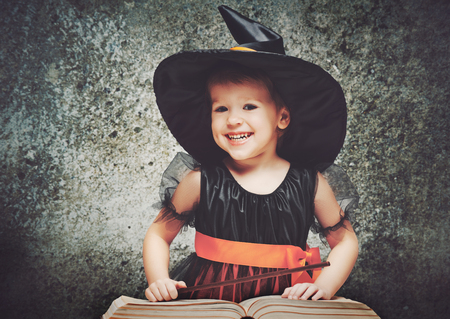 Halloween. cheerful little witch with a magic wand and the book conjure and laughs.の写真素材
