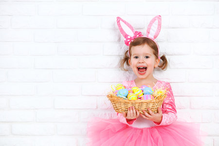 Happy child girl in a costume Easter bunny rabbit with ears and a basket of eggs